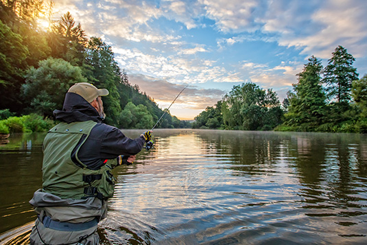 a man holding a fishing rod in a river