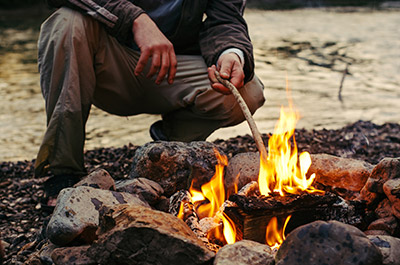 A person is adding a stick to a fire