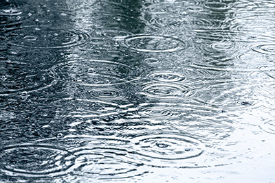 A picture of raindrops making ripples on a gray surface